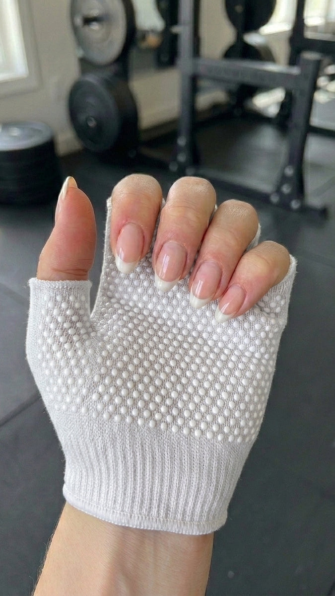 White fingerless glove with textured palm held in a gym setting