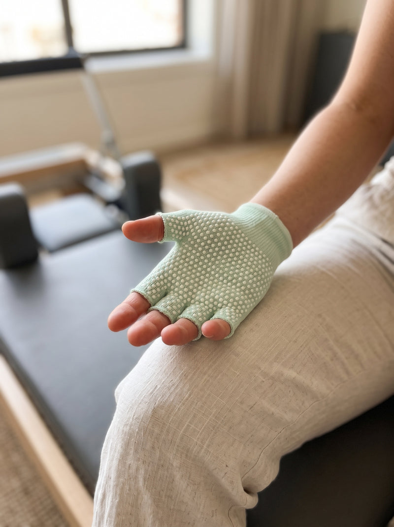 Palm of a hand in a mint SoftGrip glove resting on a thigh, raised grip dots across the palm and fingers