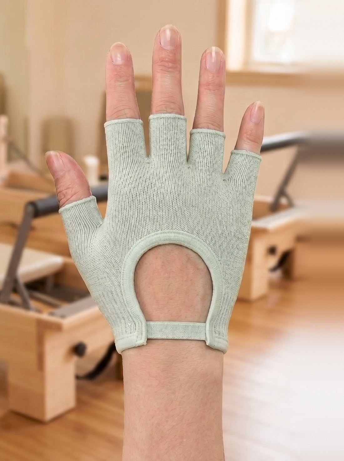 The same hand in an Oat SoftGrip Pilates Glove, silicone grip dots across the palm